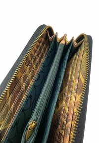 Billetera de cuero negro con cremallera dorada, que cuenta con múltiples compartimentos forrados con tela verde y estampada. Interior detallado con diversas texturas.