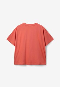 T-shirt surdimensionné en coton corail, avec des manches courtes, un col rond et une texture lisse sans motifs ni accents visibles.