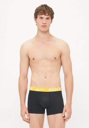 Schwarze Boxershorts mit einem gelben Nike-Logo am Bund. Der Stoff wirkt glatt mit einer engen Passform und minimalen Nähten.