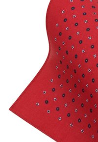 Czerwona tkanina z powtarzającym się wzorem małych białych kwiatków i ciemnoniebieskich kropek. Tekstura jest gładka i lekko błyszcząca.