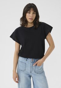 Black short-sleeve t-shirt with eyelet detailing on sleeves, paired with light blue high-waisted denim jeans. Simple, casual design.