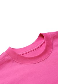 Kortærmet pink bomulds T-shirt med rund ribbet krave. Glat tekstur, synlige sømme på krave og kant, let kurve ved kanten.