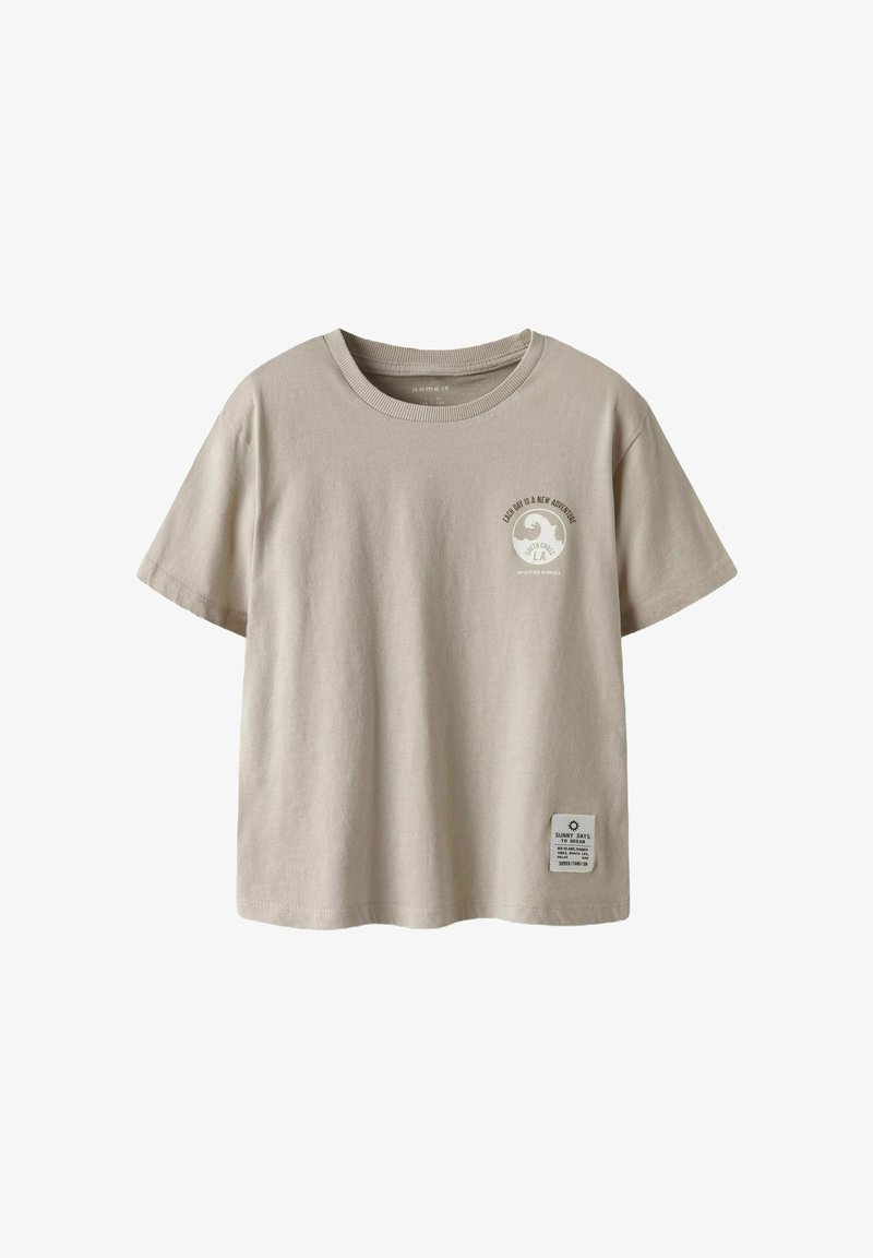 Šviesiai ruda medvilninė marškinėliai su trumpomis rankovėmis, apvaliu iškirpimu, su apskritimu grafiniu spaudiniu ant krūtinės ir etikete ant apačios.