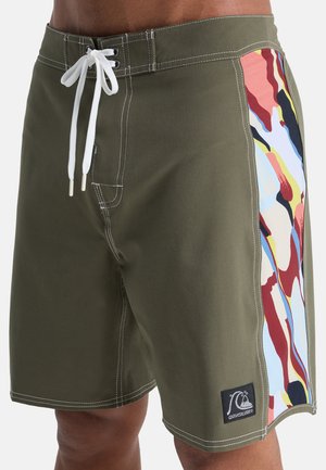 Olivovo zelené plavkové šortky s bielym sťahovacím šnúrkou, bočným panelom so vzorom v abstraktných viacfarebných farbách a značkovou čiernou záplatou.
