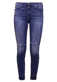 Jeans ajustados de mezclilla azul oscuro con detalles desgastados, que presentan desgarros en las rodillas, diseño clásico de cinco bolsillos y cierre de cremallera con botón.