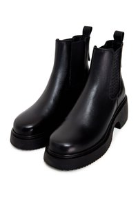 Botas de tobillo de cuero negro con un acabado suave, panel lateral elástico y suela de goma gruesa. Incluyen tiradores para facilitar su uso.