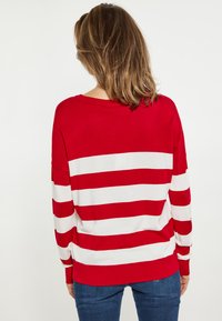 Rood-witte gestreepte trui met lange mouwen en een relaxte pasvorm. Gebreide textuur, ronde halslijn en contrasterende strepen op de rug.