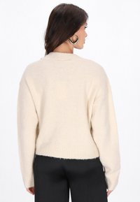 Maglione beige e morbido con orlo a coste e spalle ampie e cadenti. Progettato con una vestibilità rilassata e una texture sottile.