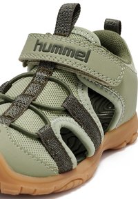 Grüne Sportsandale aus Mesh-Material mit strukturierten Akzenten und Gummisohle. Verfügt über einen verstellbaren Riemen und offene Seiten für zusätzliche Belüftung.