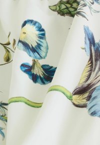 Blumenstoff mit blauen Blumen und grünen Stielen auf einem weißen Hintergrund, der eine glatte Textur und ein detailliertes botanisches Design zeigt.