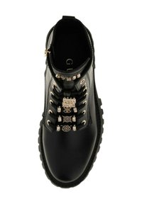 Stivale di pelle nera con suola spessa, caratterizzato da lacci neri infilati attraverso occhielli decorativi dorati e quattro eleganti ciondoli dorati sui lacci.