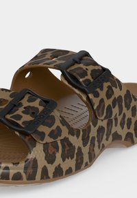 Καφέ και μαύρο πέδιλο Crocs με λεοπάρ σχέδιο, δύο ρυθμιζόμενες μαύρες αγκράφες και υφασμένο πέλμα.