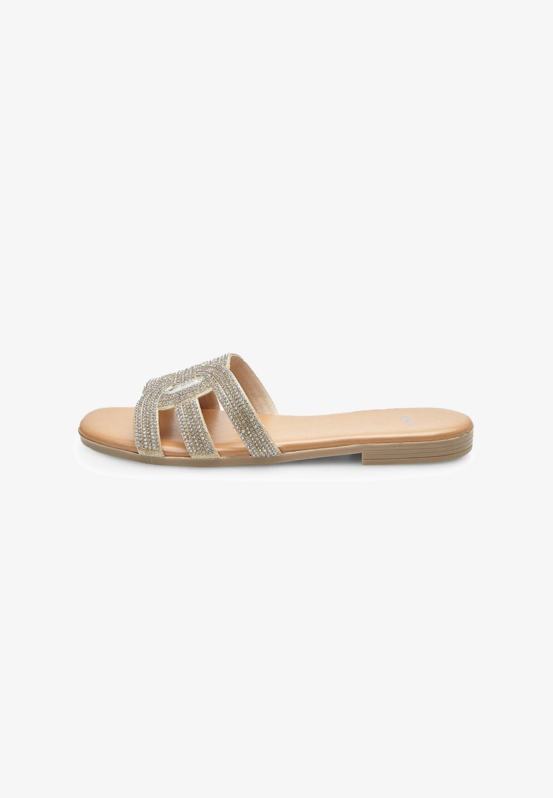 Flat sandals featuring a beige base with a crisscross vamp adorned with silver rhinestone embellishments. Simple design with no heel.