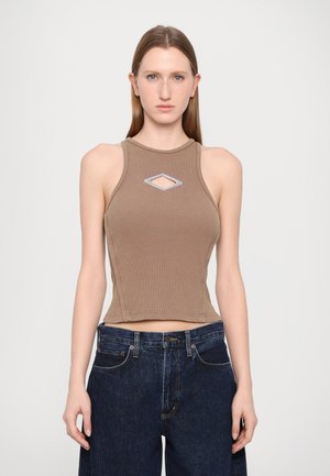 Khaki ribbovaná bezramenná crop top se šikmým výřezem na hrudi, spárovaná s tmavými denimovými širokými nohavicemi.