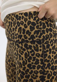 Leggings met luipaardprint in een tan en zwart kleurenschema, met een hoge tailleband en een gladde, rekbare stof textuur.