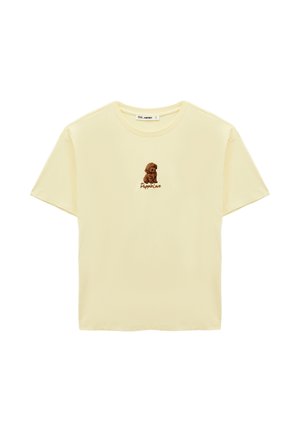 Jasnożółta koszulka z krótkim rękawem z małą ilustracją brązowego szczeniaczka i napisem "Puppie Love" na środku klatki piersiowej.