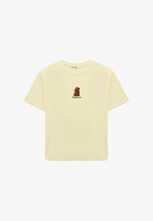 Jasnożółta koszulka z krótkim rękawem z małą ilustracją brązowego szczeniaczka i napisem "Puppie Love" na środku klatki piersiowej.