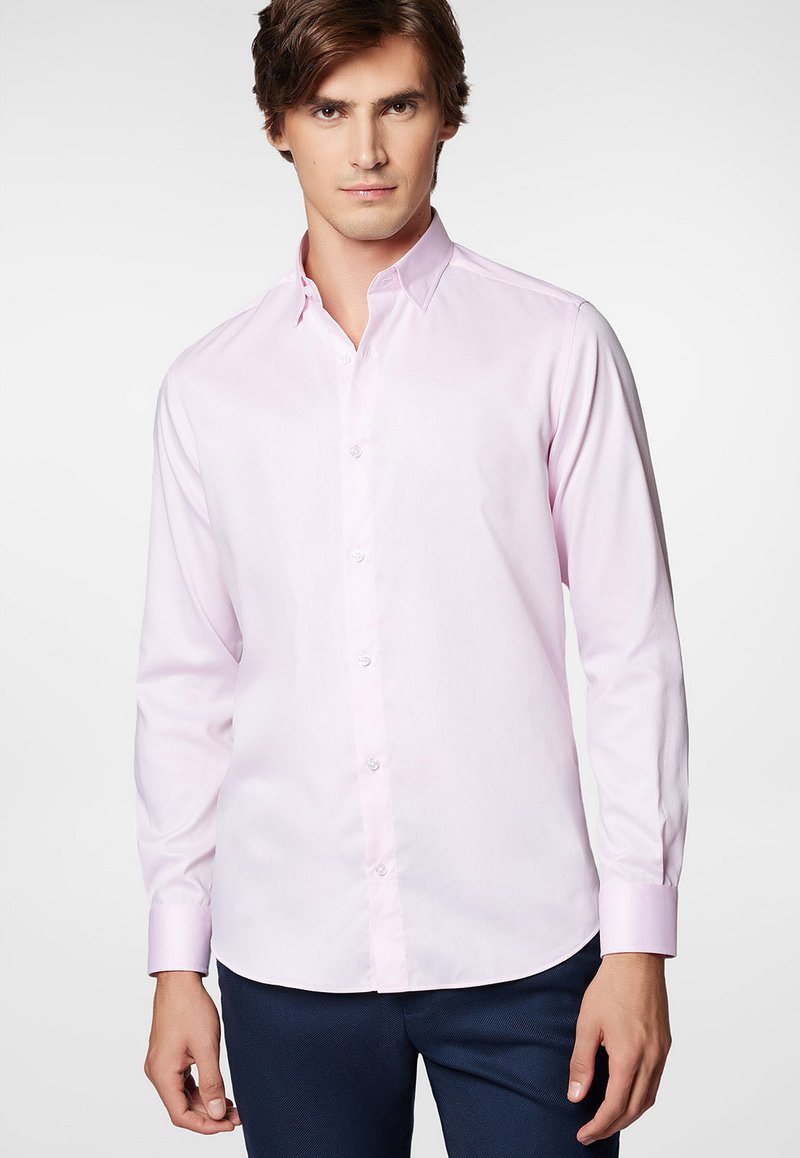 Jasnoróżowa, długosleeve koszula zapinana na guziki z wydłużonym kołnierzykiem, przednim zapięciem i regulowanymi mankietami, wykonana z gładkiego materiału.