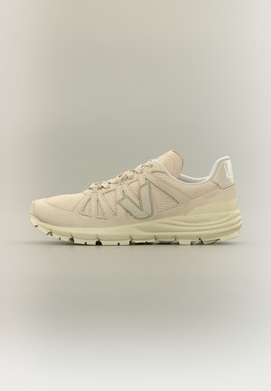 Beige lage sneaker met een bovenwerk van mesh en suède, voorzien van een merk "V" aan de zijkant, een gewatteerde zool en een Vibram-buitenzool, weergegeven in zijaanzicht.