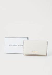 Valge nahkrahakott, millel on krobeline tekstuur, esindades kuldset "MICHAEL KORS" logo. Saadaval koos hõbedaste aktsentidega karbiga.