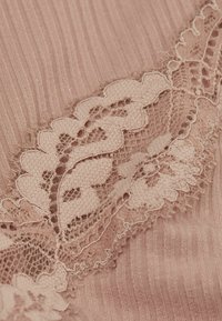 Tela de color rosa empolvado con textura acanalada y delicado borde de encaje con patrones florales, que destacan los intrincados detalles y el acabado suave.
