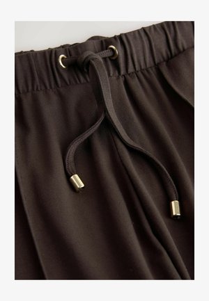 Brūnas elastīgas vidukļa bikses ar auklu, kuras galiem ir zelta metāla uzgaļi, mīksta tekstūra un gluda auduma virsma.