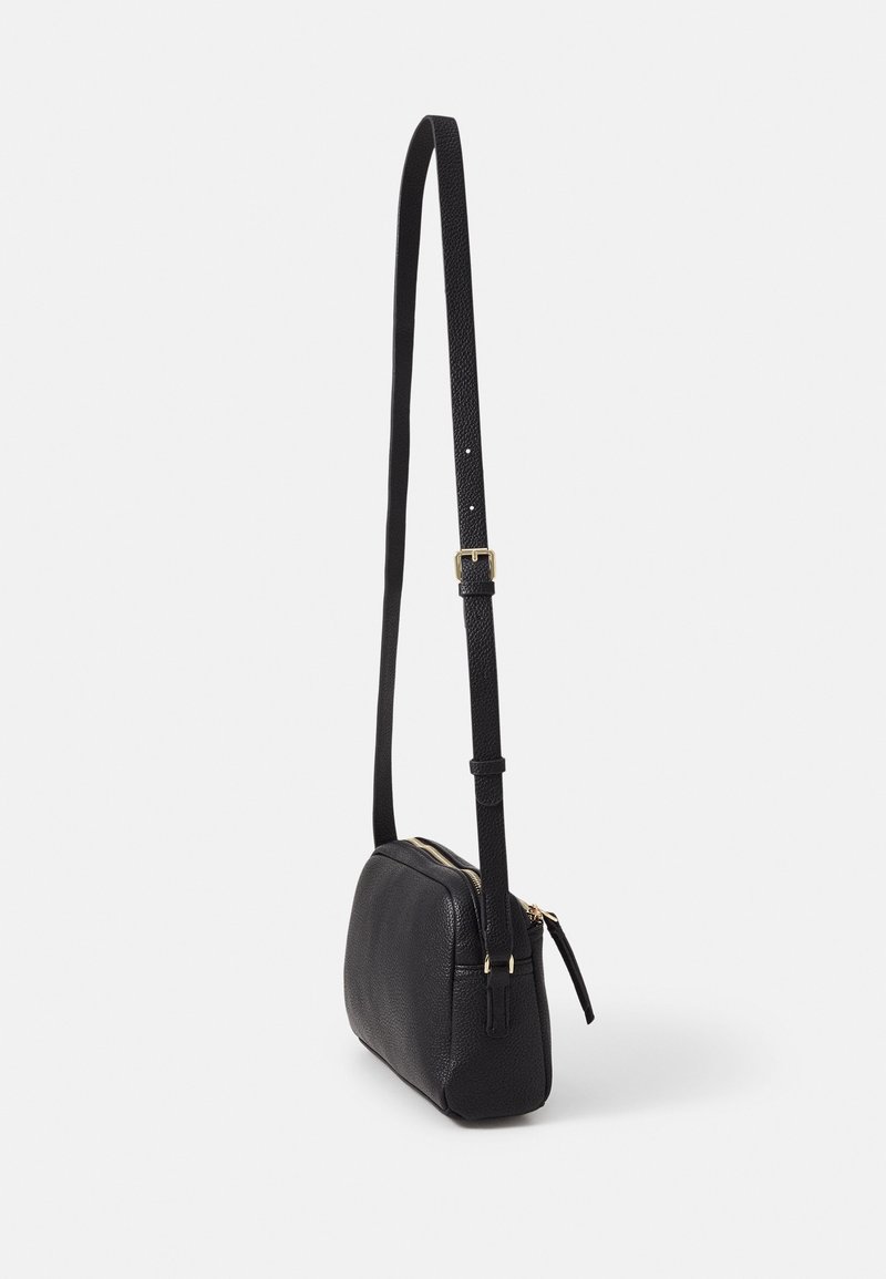 Borsa a tracolla in pelle nera con zip nella parte superiore, forma rettangolare piatta, superficie testurizzata e tracolla regolabile con hardware dorato.