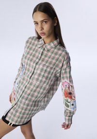 Camicia a quadri button-up in rosa e verde con motivi floreali sulle maniche; presenta una tasca sul petto e una vestibilità comoda.