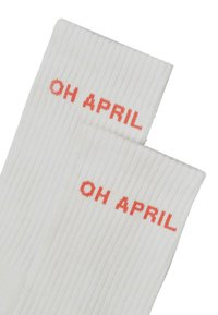 Baltas ribots zeķes ar tekstu "OH APRIL" kontrastējošā oranžā diegā. Vienkāršs dizains ar gludu tekstūru un vienmērīgu šūšanu.