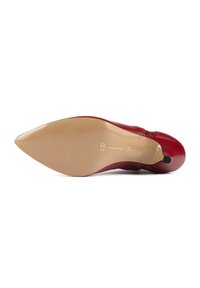 Scarpa con tacco alto rossa, punta affusolata e tomaia in pelle liscia. Presenta un tacco sottile e una suola texturizzata di colore chiaro.