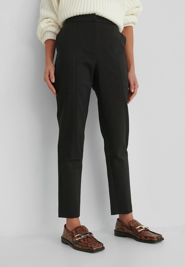 Svarta skräddarsydda byxor med en slimmad design, som har hög midja och rak passform. Tillsammans med bruna loafers i ormtryck.