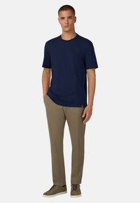 Námořnické tričko s krátkým rukávem v kombinaci s béžovými kalhotami a šedými teniskami. Tričko má kulatý výstřih a volný střih.