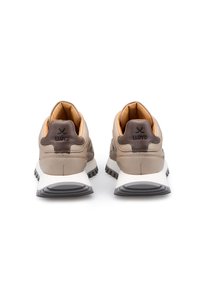 Scarpe sportive in pelle beige con accenti marroni, collarino imbottito e suola in gomma grigia. Marchio sul tallone e dettagli testurizzati visibili.