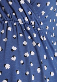 Tecido azul com poás florais brancos e pretos, apresentando um design envolvente e textura franzida na cintura.