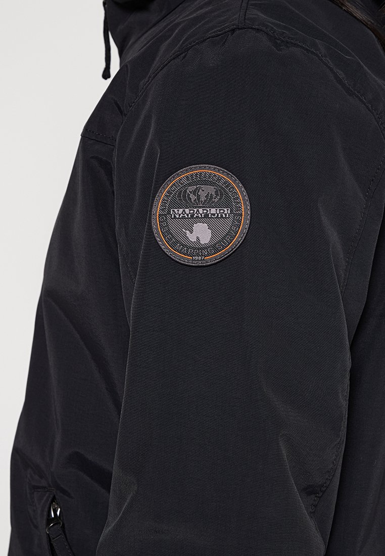 Giacca nera con una toppa rotonda con il testo "NAPAPIJRI" e un design di un globo sulla parte superiore della manica, realizzata in tessuto testurizzato.