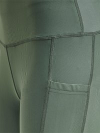 Groene sportleggings met een gladde textuur, platte naden en een zijzak. Het ontwerp is aansluitend en naadloos.