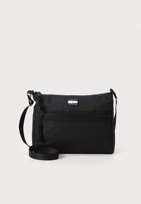Musta crossbody-laukku, joka on valmistettu teksturoidusta kankaasta ja jossa on vetoketjullinen suljin, etutasku vetoketjulla ja merkitty logoplässi. Mukana säädettävä olkahihna.