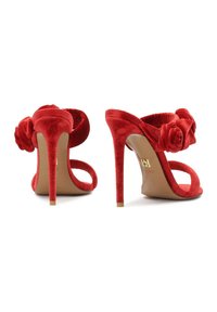 Sandales à talons hauts en daim rouge avec dos ouvert, ornées d'accents floraux, au design épuré et aux talons aiguilles fins.
