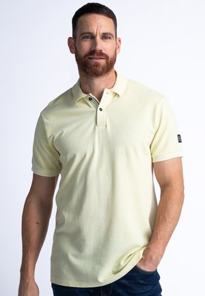 Hellgelbes Polo-Shirt mit kurzen Ärmeln, einem gerippten Kragen und einer Knopfleiste mit drei Knöpfen. Verfügt über ein kleines schwarzes Logo am linken Ärmel.