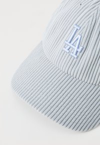 Gorra de corduroy azul claro con un logotipo bordado de "LA" en la parte frontal, inclinada ligeramente para revelar la textura y la forma.