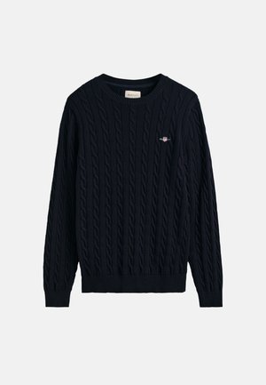 Granatowy sweter w warkocze z okrągłym dekoltem, ściągaczami przy rękawach i u dołu, z małym haftowanym logo na piersi.