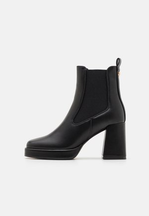 Bottines noires en cuir lisse, avec des panneaux latéraux élastiques, un talon bloc épais et un design à bout arrondi.