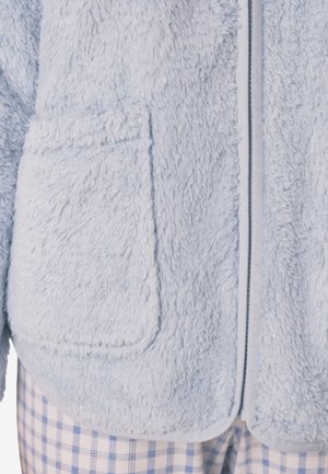 Lichtblauwe donzige fleece jas met een zachte textuur, voorzien van twee voorzakken en een ritssluiting omrand met een contrasterende bies.