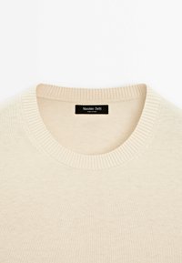 Pull beige en maille avec col rond côtelé et étiquette Massimo Dutti à l'intérieur de l'encolure.