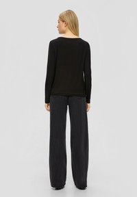 Czarna bluzka z długim rękawem i okrągłym dekoltem, w połączeniu z szerokimi spodniami o wysokim stanie w ciemnoszarym kolorze. Prosty design i gładka tekstura.