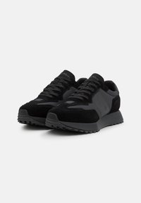 Black athletic sneakers featuring a mix of suede and synthetic materials, with a textured rubber sole and flat laces for closure.