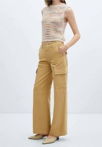 Strick-Tops ohne Ärmel mit mehrfarbigem Muster, kombiniert mit weit geschnittenen, khakifarbigen Cargo-Hosen mit seitlichen Taschen und einem Knopfverschluss.