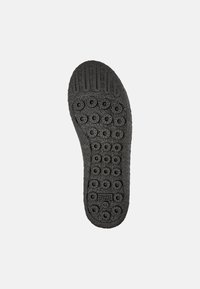 Suela de zapato de goma negra con patrones de pisada circulares, una superficie texturizada y marca grabada. Tacón redondeado con marca de tamaño visible.