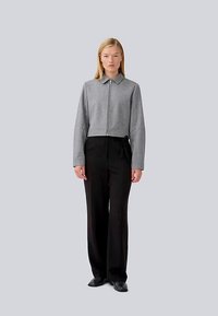 Szürke, cropped dzseki, elöl cipzárral, gallérral és széles ujjal, fekete nadrággal párosítva. Sima textúrájú és testre szabott szabású.