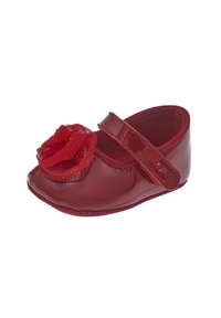 Zapato de charol rojo con punta redonda, un acento de flor de encaje texturizada roja y una correa de velcro. Forro interior suave.